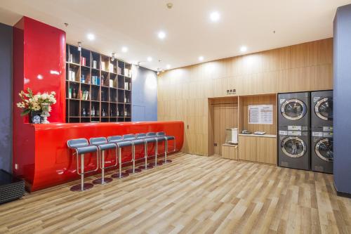 a laundry room with a row of chairs and a red wall at 北京刘家窑地铁站万信至格酒店 in Beijing