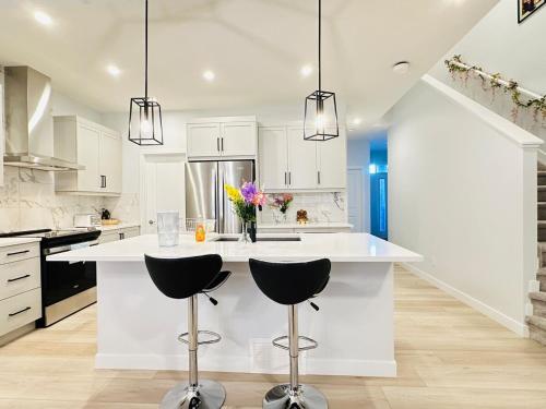 a kitchen with a white island with two stools at Relax at The Hills at Ellerslie in Edmonton