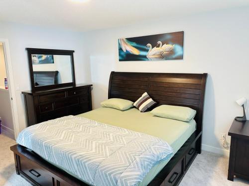 a bedroom with a bed and a dresser and a mirror at Relax at The Hills at Ellerslie in Edmonton