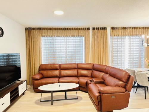 a living room with a brown leather couch and a table at Relax at The Hills at Ellerslie in Edmonton