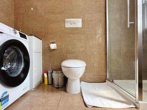 a bathroom with a toilet and a washing machine at City Breeze BNB - Center Location in Hobart