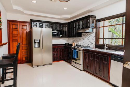 a kitchen with wooden cabinets and a stainless steel refrigerator at Luxury Oasis in Las Colinas- Elegant 3-Bedroom Villa in Managua