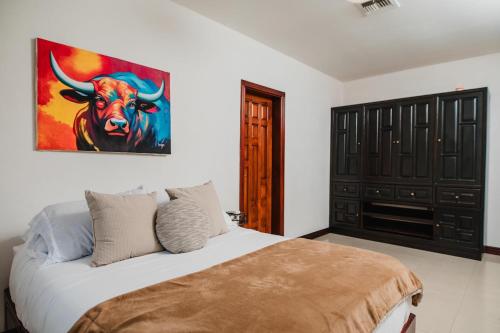 a bedroom with a bed with a painting of a bull at Luxury Oasis in Las Colinas- Elegant 3-Bedroom Villa in Managua