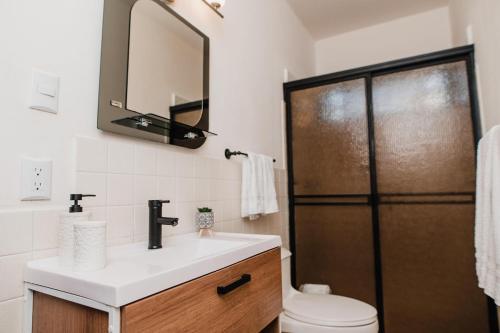a bathroom with a sink and a toilet and a mirror at Luxury Oasis in Las Colinas- Elegant 3-Bedroom Villa in Managua