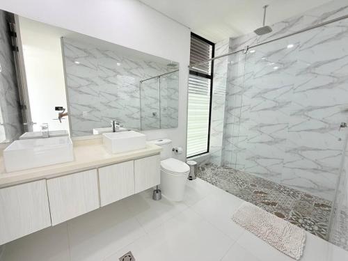 a white bathroom with two sinks and a shower at Casa con piscina y BBQ en Lagos del Peñón Girardot in Girardot