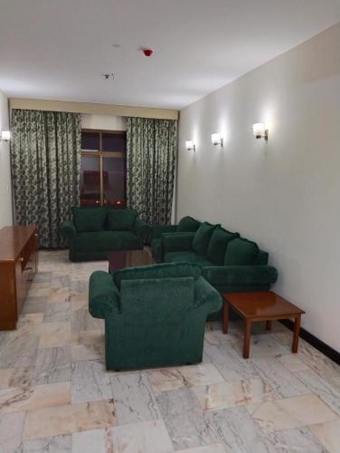 ein großes Wohnzimmer mit grünen Sofas und Tischen in der Unterkunft Al nahda tower in Salalah