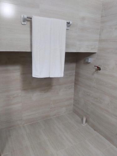 ein Badezimmer mit einem weißen Handtuch, das an der Wand hängt in der Unterkunft Al nahda tower in Salalah
