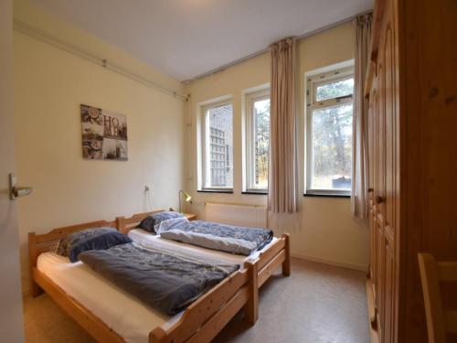 two beds in a room with two windows at Skyscraper apartment on the highest point with beautiful view in Bergen aan Zee