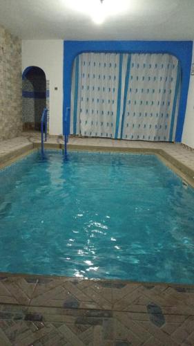 a swimming pool with blue water in a building at Dar EL Biad Appt 3 in Stehat