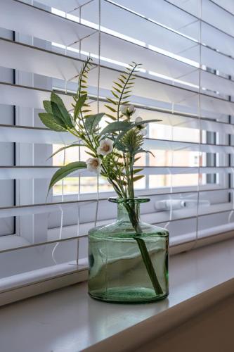 a vase with flowers in it sitting on a window sill at Walk to Liverpool Airport - Luxury Stay with EV Charge - Fast WiFi in Liverpool