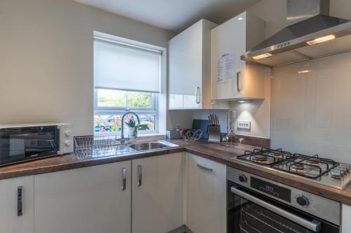 a kitchen with white cabinets and a sink and a stove at Walk to Liverpool Airport - Luxury Stay with EV Charge - Fast WiFi in Liverpool
