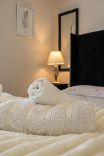 a white towel laying on top of a bed at Walk to Liverpool Airport - Luxury Stay with EV Charge - Fast WiFi in Liverpool
