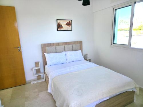 a bedroom with a large white bed with a window at Signature Villa à la Plage in Temara