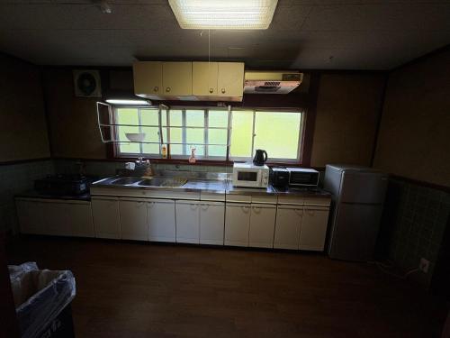 a kitchen with white cabinets and a sink and a refrigerator at 高島市一棟貸切貸別荘グループファミリーok 大人数でご利用だとお得連泊がお得BBQ可能自転車無料利用可ペット可 in Takashima