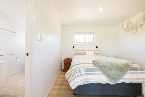 une chambre blanche avec un lit avec une couverture rayée dans l'établissement Cottage 2 Cape Keppel Beach, à Curtis Island