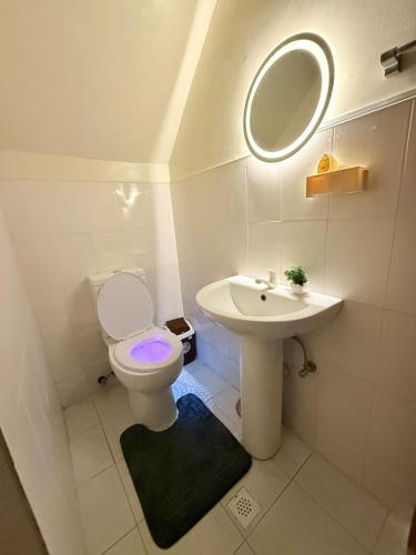 a bathroom with a toilet and a sink and a mirror at Chic &Cozy 3Bedroom House in Agus