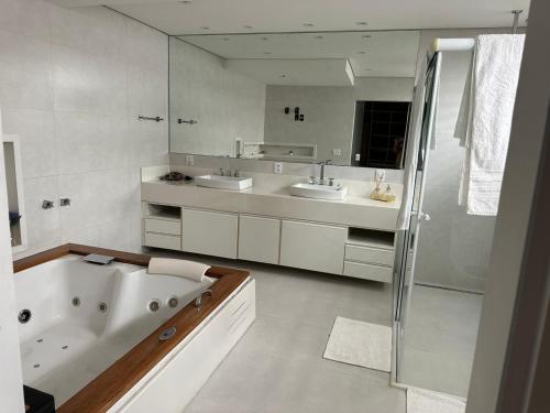 a bathroom with two sinks and a bath tub at Mansão Casa Blanca em São Roque c/ 5 vagas garagem in São Roque