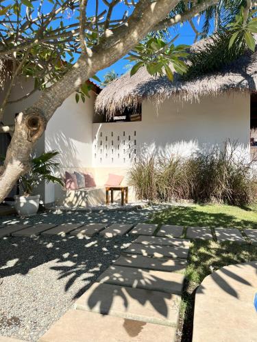 a building with a thatch roof and a bench at Villa Mila - Gili Air in Gili Air