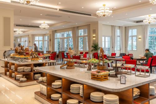 a restaurant with tables and red chairs and people at Legend Valley Hotel Ha Nam in Phủ Lý