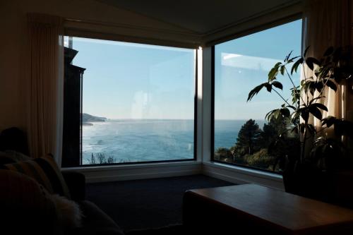 Una habitación con una gran ventana con vista al mar. en Elevated architectural home with stunning sea views, en Dunedin