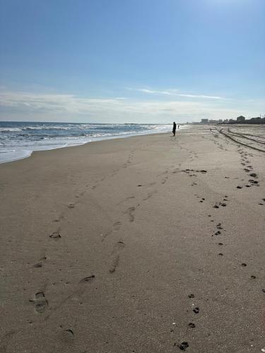 a person walking on the beach with footprints in the sand at With BBQ terrace & dog run A private house full of fun, right by the sea and surf spots in Kashima
