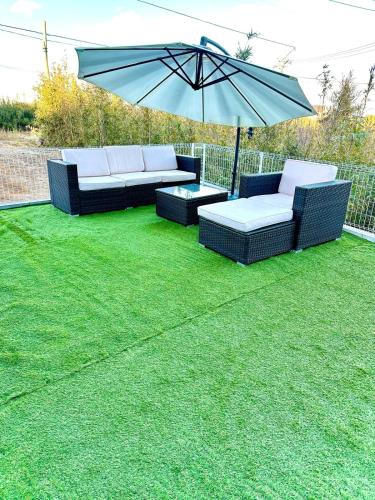 two couches and an umbrella on a lawn at With BBQ terrace & dog run A private house full of fun, right by the sea and surf spots in Kashima