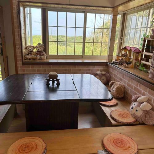 a table in a room with stuffed animals and windows at With BBQ terrace & dog run A private house full of fun, right by the sea and surf spots in Kashima