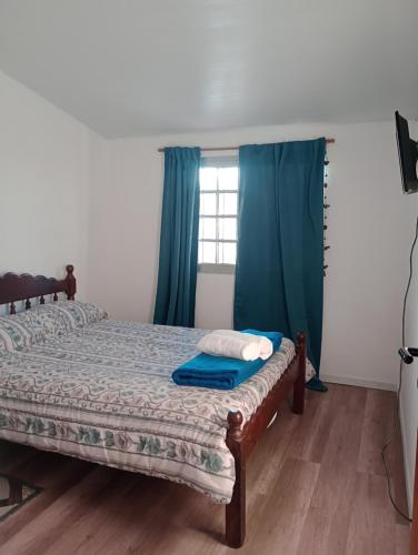 1 dormitorio con 1 cama con cortinas azules y ventana en Mi Departamentito, en Federación