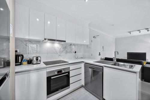 a white kitchen with a sink and a stove at Comfortable 2BR Stay in Rockingham in Rockingham