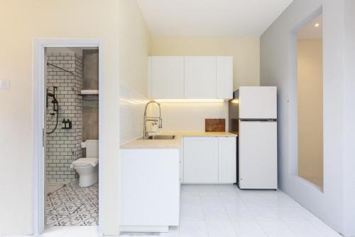 a white kitchen with a sink and a refrigerator at De Luma-Cozy 2Bedroom Landed House, Bukit Mertajam in Bukit Mertajam