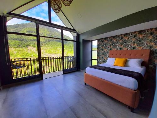 a bedroom with a bed and a balcony with windows at Hotel Nido de Pájaro in Los Naranjos