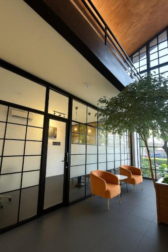 a room with two chairs and a table and windows at Nunia Tamansari Hotel in Kumprung