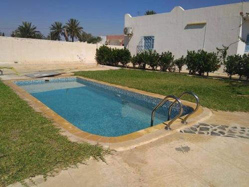 a swimming pool in front of a house at Appartement, séjour Djerba 4 in Arkou