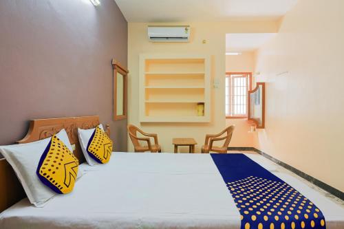a bedroom with a bed with yellow and blue pillows at Hotel O Vel Vel Guest House in Palani