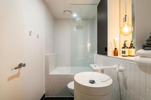 a white bathroom with a sink and a bath tub at Sleek&Stylish Corner Apt on TopFloor Southbank Vic in Melbourne