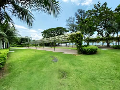 a green park with trees and a building at By The Sea Penang in Batu Ferringhi