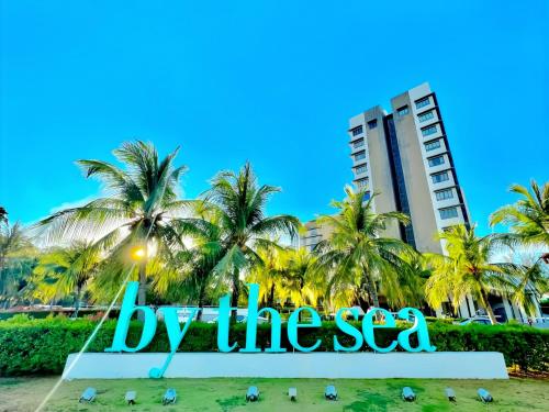 a sign in front of a beach with palm trees at By The Sea Penang in Batu Ferringhi