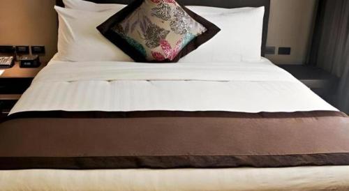 a bed with white sheets and a pillow on it at F1 Hotel Manila in Manila