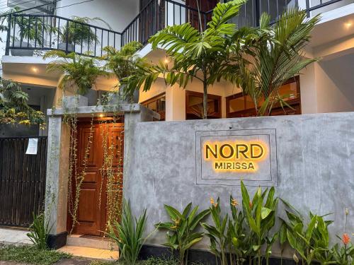 a sign on the side of a building with a nord embassy sign at Nord Mirissa in Mirissa