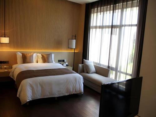 a bedroom with a bed and a couch and a television at Xian Elegant Oriental Hotel in Xi'an