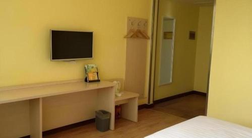 a room with a television on a wall with a desk at 7 Days Inn Nanjing Gaochun Metro Station in Gaochun