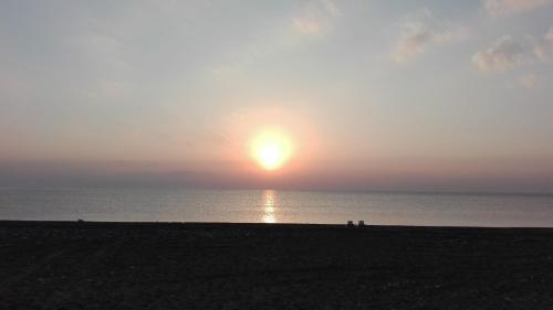 a sunset at the beach with people walking on the beach at Rosemary Pansiyon in Cıralı