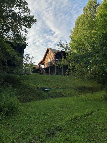 a house sitting on top of a lush green field at Laurel Lake Cabins in Corbin