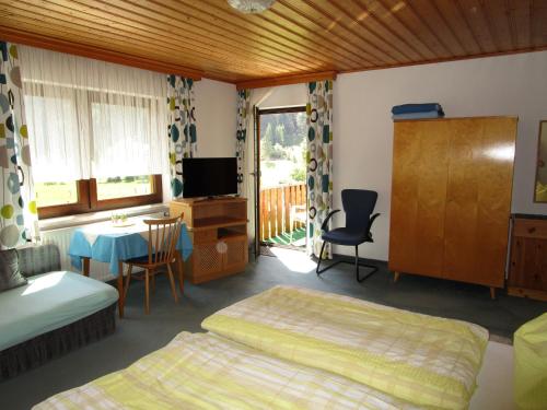 a bedroom with two beds and a table and a television at Gästehaus Sams in Gosau