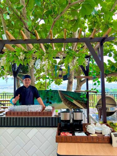 a man is standing behind a counter with food at Castle View Hotel Samal in Magamomo