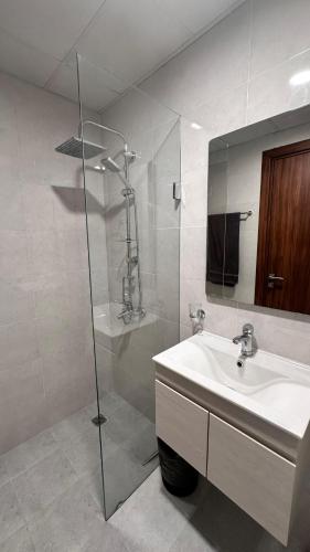a bathroom with a sink and a shower with a mirror at Royal Al Arfan Apartment in Muscat