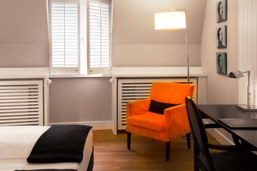 a bedroom with an orange chair and a desk at Hotel Victoria in Frankfurt/Main