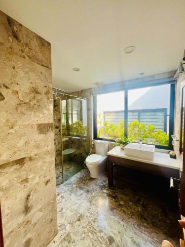 a bathroom with a toilet and a sink and a window at Flamigo Dai Lai Resort - Villa Chủ Tự Doanh in Ngọc Quang