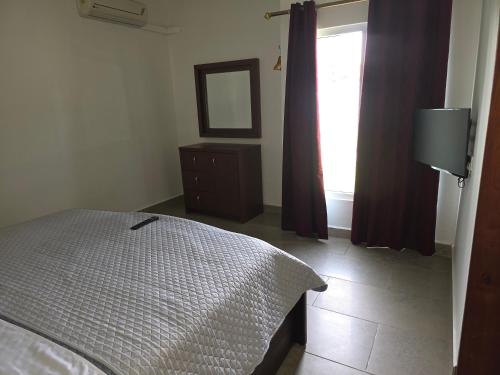 a bedroom with a bed and a window and a mirror at My dad's cottage in Takoradi