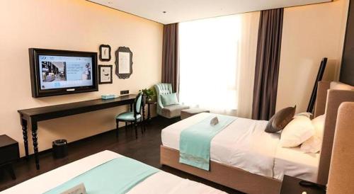 a hotel room with a bed and a desk and a television at Xana Hotelle·Ji'nan Hi-tech Zone Century Avenue Tangye in Jinan